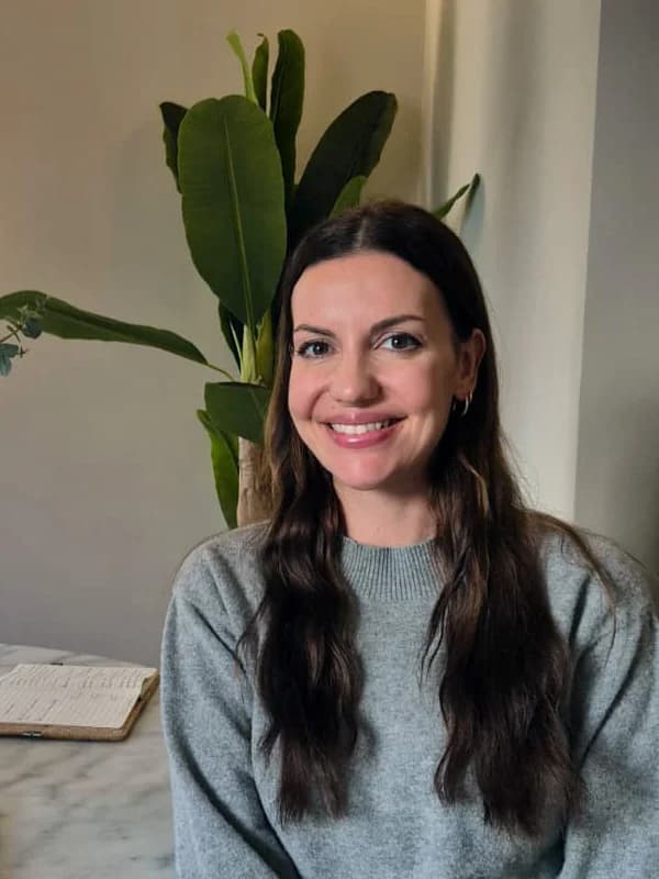 Melanie Hoberg, lächelnd am Tisch in einem hellen Raum mit Pflanzen